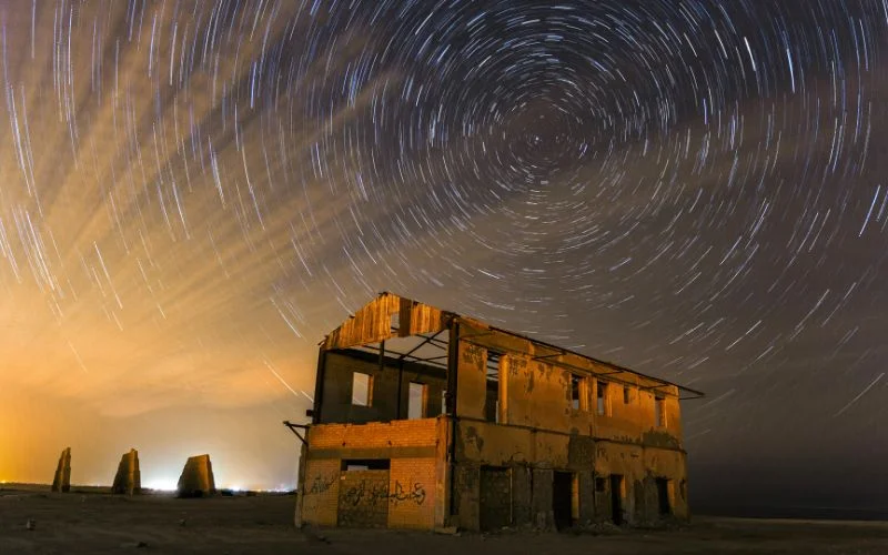 Circular star trails in the night sky above an old abandoned building, a long exposure astrophotography example