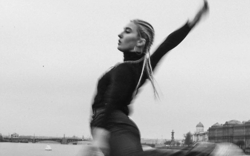 Black and white photo of a dancer with motion blur on her arm, an artistic slow shutter speed effect