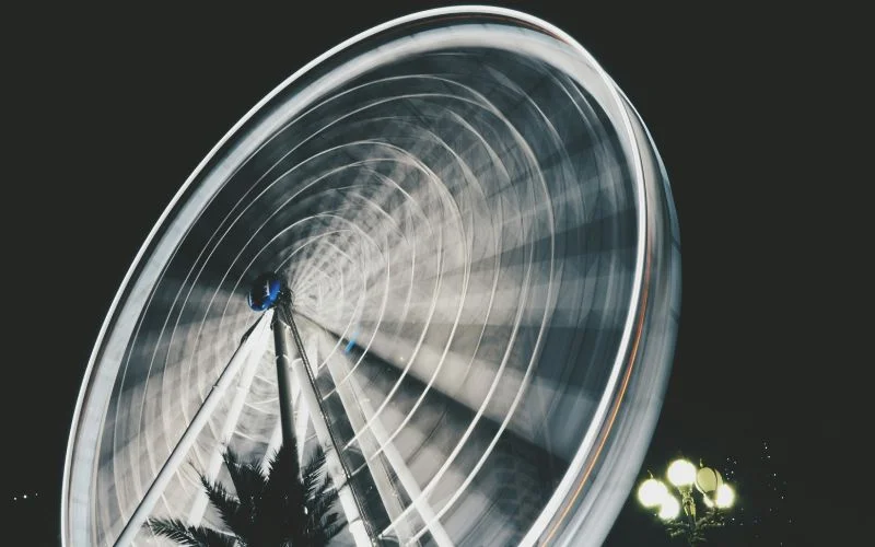 Ferris wheel captured with a slow shutter speed, creating a smooth circular light blur