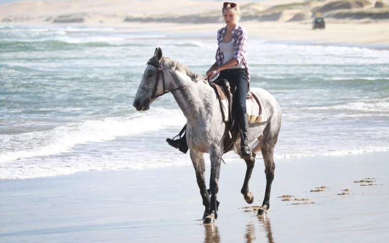 Woman riding a horse along the shoreline, frozen sharply at 1/2000 sec shutter speed