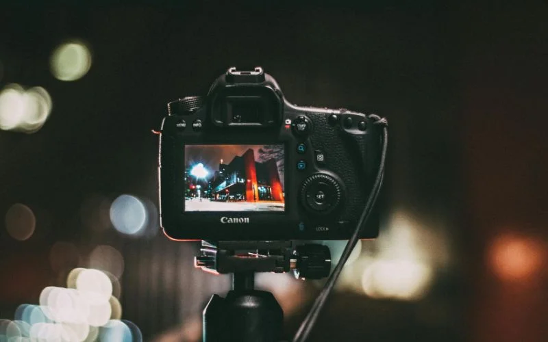 Photographer holding a camera at night with blurred bokeh lights, illustrating what is shutter speed in photography