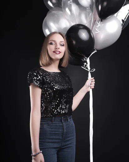 Classy 30th birthday photoshoot of a woman in a black sequin top holding black and white balloons