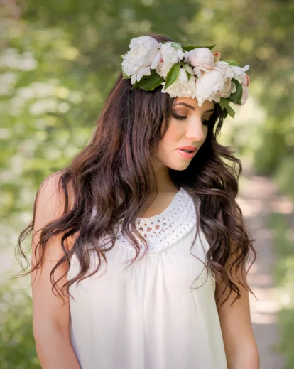Woman wearing a flower crown and white dress in a garden setting