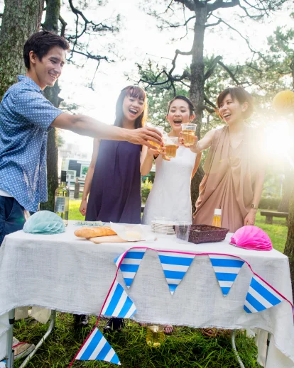 Family and friends gathered around a picnic table outdoors, with a close-up of string bunting flags
