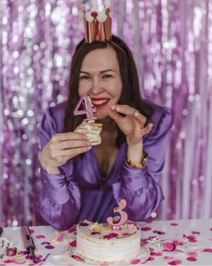 Creative 30th birthday photoshoot of a woman in a purple sequin outfit and crown with a birthday cake
