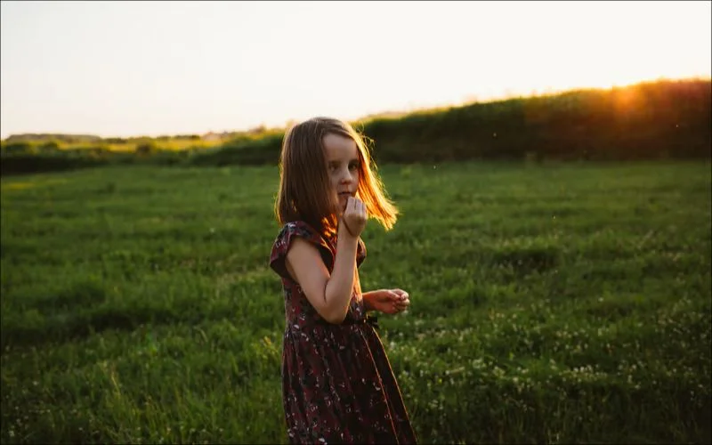 Woman walking through a green field at sunset, used to illustrate golden hour photography tips for planning with apps